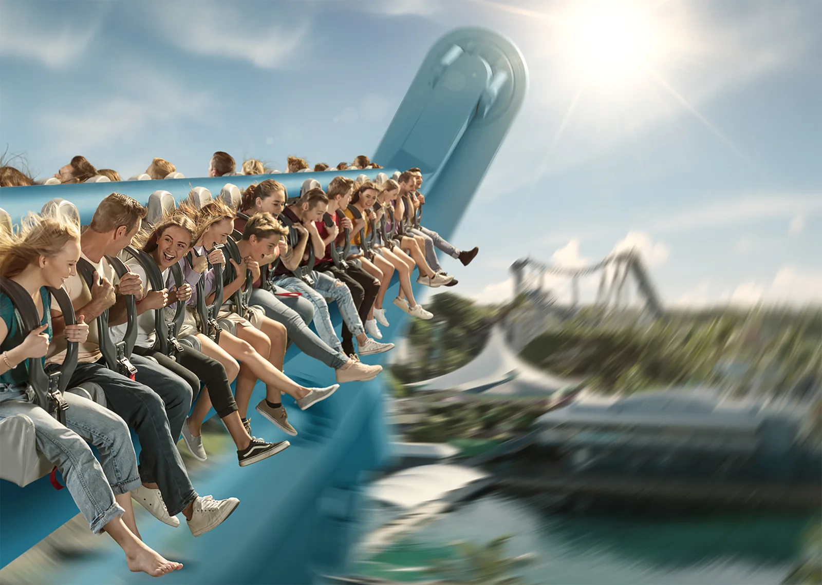 Riders laughing and screaming on a swinging theme park ride, legs dangling, with the park blurred below