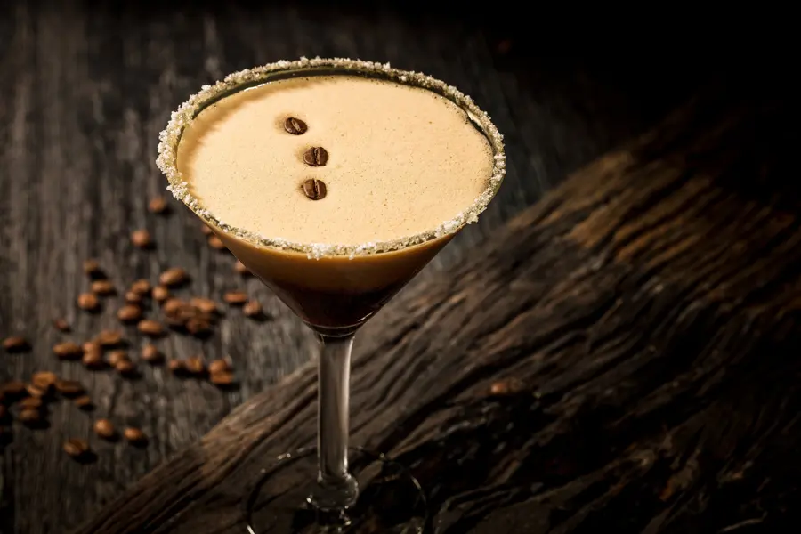 Espresso martini on dark timber with coffee beans